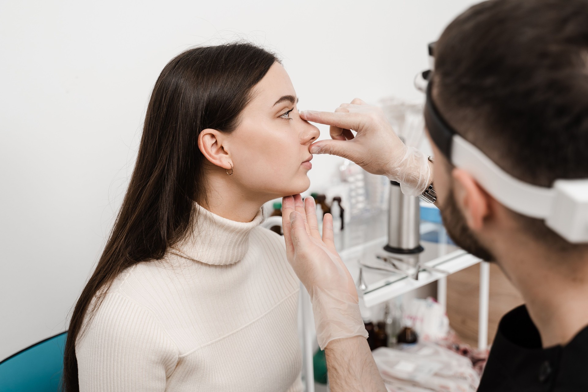 Rhinoplasty is reshaping nose surgery for change appearance of the nose and improve breathing. ENT doctor is touching nose and consulting girl patient in medical clinic before septoplasty surgery.